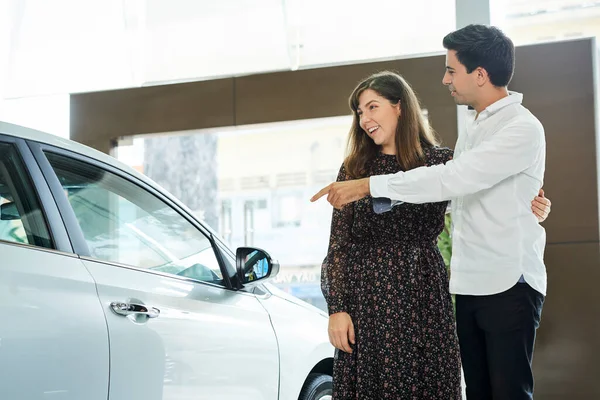 Jovem Apontando Para Carro Novo Mostrando Para Sua Esposa Enquanto — Fotografia de Stock