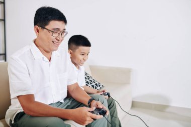 Olgun Vietnamlı bir adam, küçük oğluyla evde oyun oynamaktan zevk alıyor.