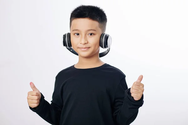 带着耳机听音乐和竖起大拇指笑的越南男孩的工作室肖像 — 图库照片