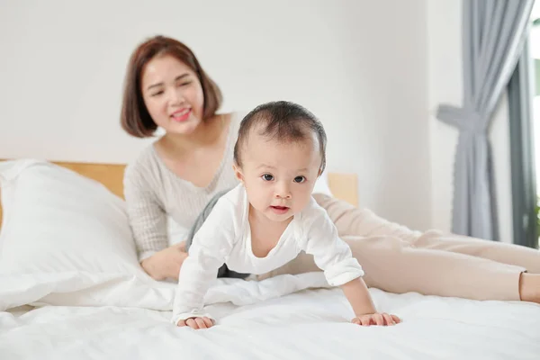 Młoda Azjatka Odpoczywa Łóżku Patrzy Swoje Urocze Pełzające Dziecko — Zdjęcie stockowe
