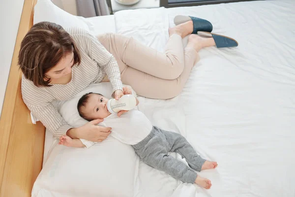 Madre Joven Alimentando Bebé Con Fórmula Biberón Cuando Relajan Cama — Foto de Stock