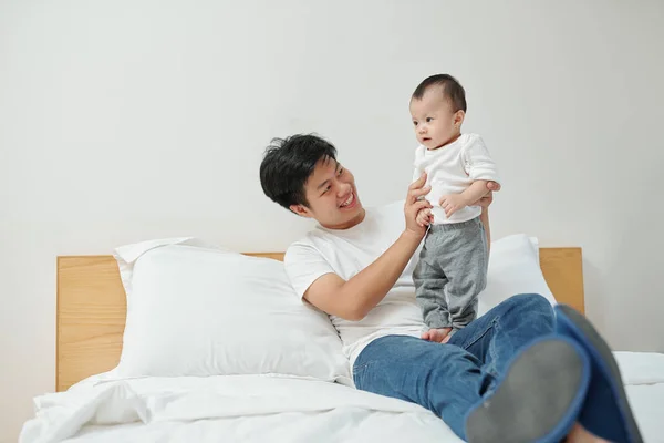 Fröhlicher Junger Vietnamese Sitzt Auf Bett Und Spielt Mit Entzückender — Stockfoto