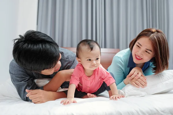 Happy Young Parents Lying Bed Looking Cute Crawling Little Daughter — Stock Photo, Image
