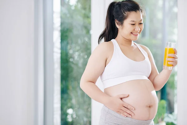 亚洲怀孕的年轻女子 早上运动后喝新鲜橙汁 摸肚皮 — 图库照片