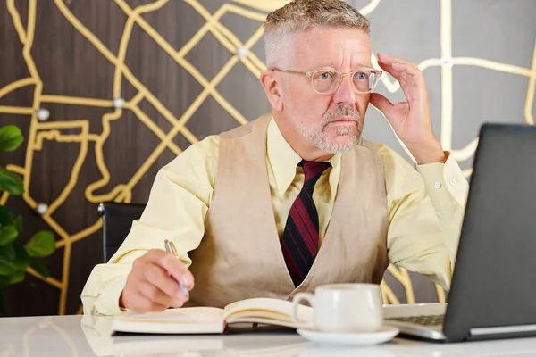 Serious Mature Entrepreneur Adjusting Glasses Reading Shockingly Poor Figures Annual — Stock Photo, Image