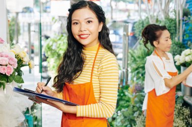 Çiçekçinin açılışı için her şeyin hazır olup olmadığını kontrol ederken güzel Vietnamlı çiçekçi notlar alıyor.