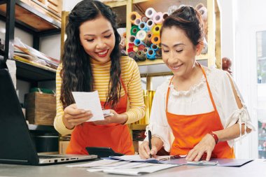 Gülümseyen Vietnamlı çiçekçiler faturaları ve satış makbuzlarını kontrol ediyor ve defter tutuyorlar.
