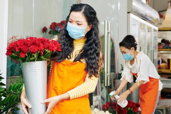 Joven Florista Asiática Máscara Médica Mirando Cubo Rosas Rojas Frescas —  Fotos de Stock