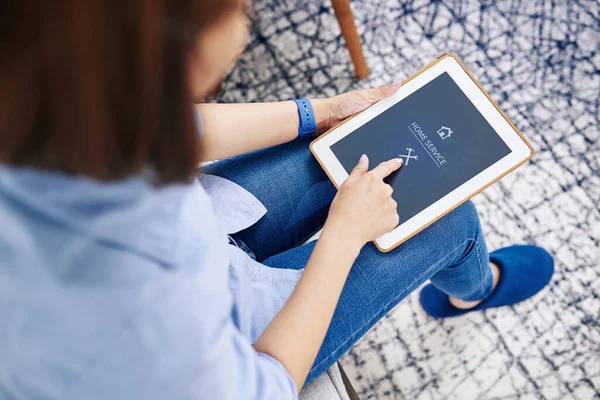 Ev hanımı, tesisatçı ya da tamirciyle iletişim kurmak için tablet bilgisayarında ev servisi uygulaması kullanıyor.