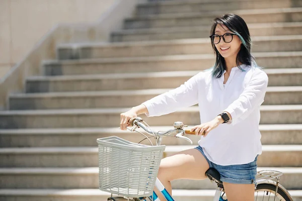 階段の前に自転車に座って青と黒の髪を持つ魅力的な若い中国人女性 — ストック写真