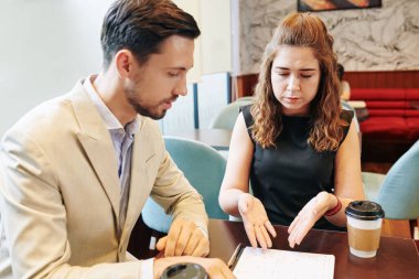 Mutsuz genç bayan girişimci toplantıda iş ortağıyla raporları tartışıyor.