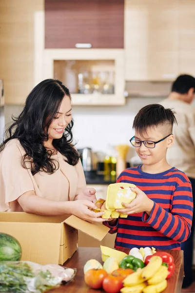 Preteen Vietnamese Boy Helping Mother Take Groceries Out Cardboard Box — Stock Photo, Image