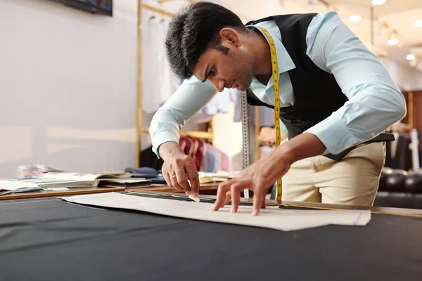 Konzentrierte Junge Indische Schneiderin Zeichnet Schnittmuster Auf Schwarzem Stoff Nach — Stockfoto