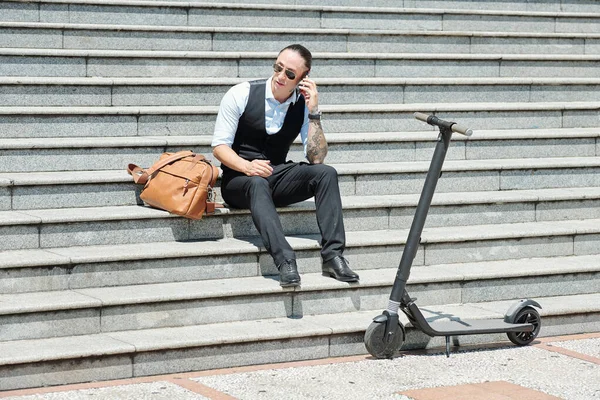 Seriöser Unternehmer Sitzt Nach Rollerfahrt Auf Stufen Und Telefoniert — Stockfoto