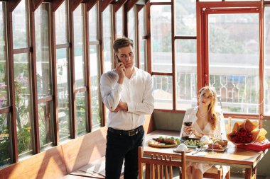 Romantik bir buluşma sırasında iş arkadaşıyla telefonda konuşan mutsuz, genç bir kadın.