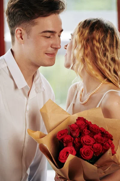 年轻女子接受花束 亲吻男友的脸颊 — 图库照片