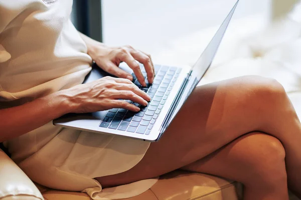 穿着丝绸迷你裙在家里笔记本电脑上工作的年轻女性的特写形象 — 图库照片