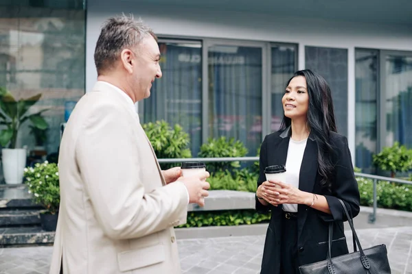 美しい若いアジアのビジネスマンの笑顔彼らは屋外でコーヒーを飲むとき彼女のシニア同僚のアイデアを聞いて — ストック写真