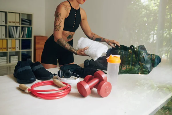 女运动员包装体操袋 把毛巾 振动器 耳机和运动鞋放进里面的剪影 — 图库照片
