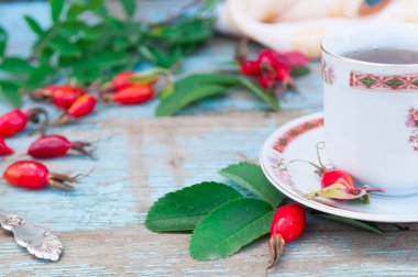 Geleneksel bir dogrose süsleme ile beyaz bir fincan çay. Eski bir ahşap arka plan kompozisyonu. Bitkisel çay. Ethnoscience. C vitamini