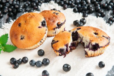 Yaban mersini ve nane ile dekore blueberry muffins. Ahşap arka plan üzerinde bir rustik tarzda fotoğraf. Bulanık.