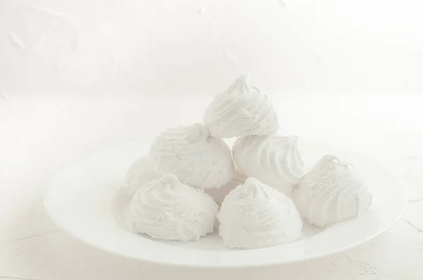 Delicate, white, fruit marshmallows. On a white background in a white plate. Isolated. Blurred background.