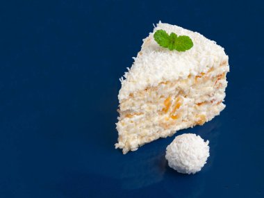 A piece of white cake with almonds and coconut chips on blue onet. clipart