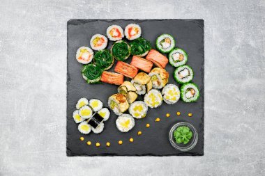 Siyah grafit tahtası ve gri arka planda yan yemekleri olan taze balık suşisi..