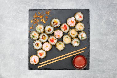 Siyah grafit tahtası ve gri arka planda yan yemekleri olan fırında sushi..