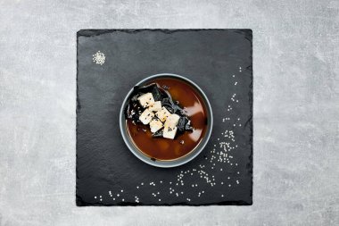 Çok iştah açıcı çok güzel dekore edilmiş siyah üzerine siyah bir tabakta siyah bir miso çorbası.