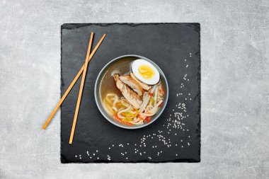 Çok güzel dekore edilmiş iştah açıcı siyah grafit tahtasında gri bir tabakta ramen çorbası..