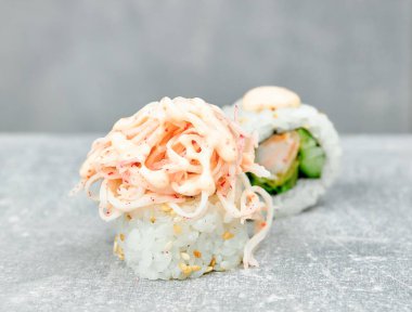 İki parça suşi uramaki, salatalık, karides ve yengeç çubuğuyla süslenmiş salata..