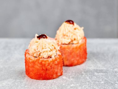 İki parça suşi uramaki, kızarmış teriyaki, karides, salata, avokado, baharat, masago havyarı, sriracha sosu..