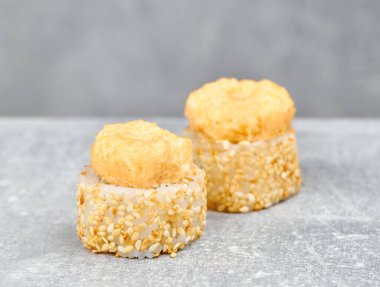 İki parça suşi, uramaki, tavuk, salatalık, krem peynir, peynir ve sarımsak sosu, susam tohumlu..