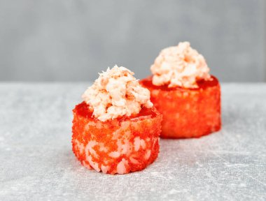 İki parça suşi uramaki, kızarmış teriyaki, karides, salata, avokado, baharat, masago havyarı, sriracha sosu..