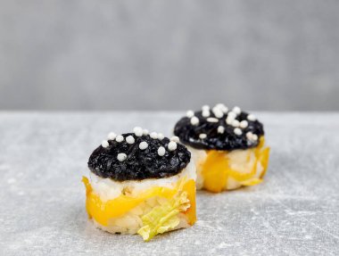 Pastırma, kabak, tavuk, çıtır soğan, salata, fırında biber, pirinç, nori, peynir ve sarımsak sosuyla pişirilmiş iki dilim suşi..