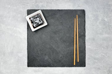 Güzel siyah granit suşi arka planda yemek çubukları ve teriyaki soslu..