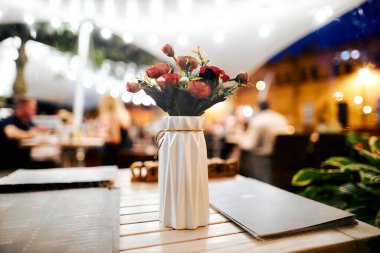 Akşamleyin terasta bir restoranda masanın üzerinde bir buket çiçek..