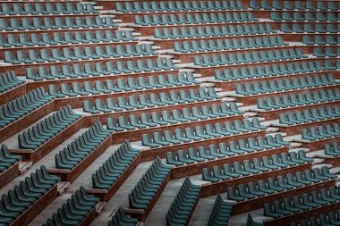 Birden çok satır ücretsiz sahipsiz koltuklarda. Boş genel arena ve konser amfitiyatro günbatımı fotoğrafı. Kırmızı tuğla ve Beyaz Traverten yapısı, gri plastik sandalye. 