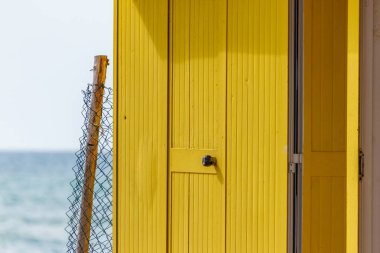 Yaz tatil yeri. Güzel parlak canlı sarı banyo kumlu sahilde ev sahipliği yapmaktadır. Boş sığınak bir güneşli ama huysuz gününde. Seaside mimarisi, boya renkli. Evsiz Peyzaj sahne. Yoksulluk ve yalnızlık kavramı.