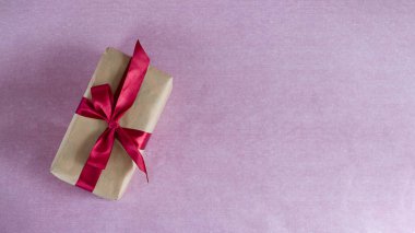 bir pembe bir hediye kutusu Kraft kağıt sarılı ve kırmızı saten kurdele (yatay olarak, kopya alanı, metin için epty yer ile bağlı