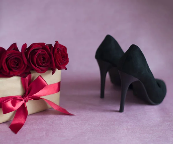 black velvet womens shoes, box tied with red ribbon, three red roses on pink background