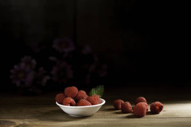 Ahududu kase ve ahşap masaya çiçek