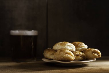 tuzlu puf böreği plaka ve bira cam ahşap masa üzerinde