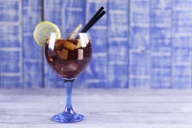 Ham meyveler, tarçın çubukları, saman ve limon içme siyah dilim ahşap masa ve mavi tahta arka plan ile İspanyol sangaree Kupası