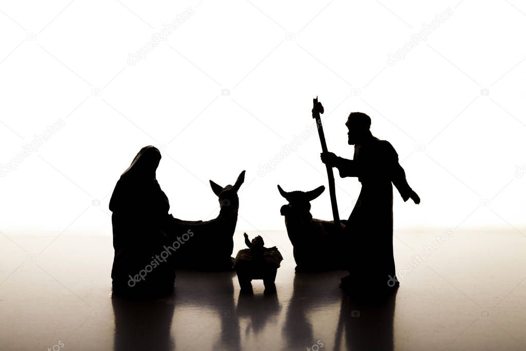 Christmas Manger scene backlighting illuminated with figures including Jesus, Mary, Joseph, cow and mule on white background