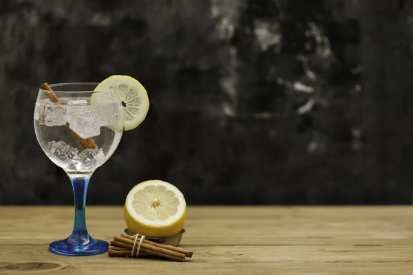 Gin tonic su vetro blu con limone e cannella sul tavolo di legno — Foto Stock