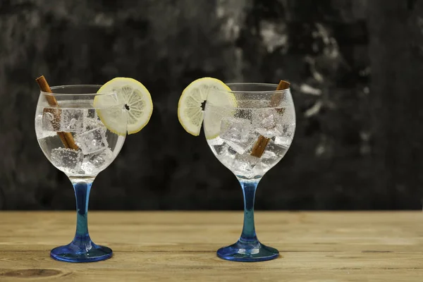 Due gin tonic su vetro blu con limone e cannella su t di legno — Foto Stock