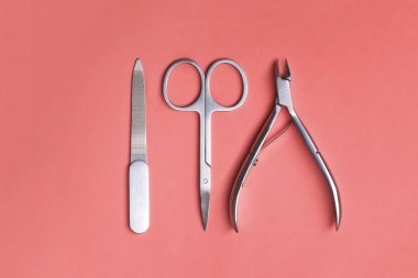 Various elegant manicure tools arranged on Living Coral background. Nail clipper, scissors and file. Color of the year 2019 concept. clipart