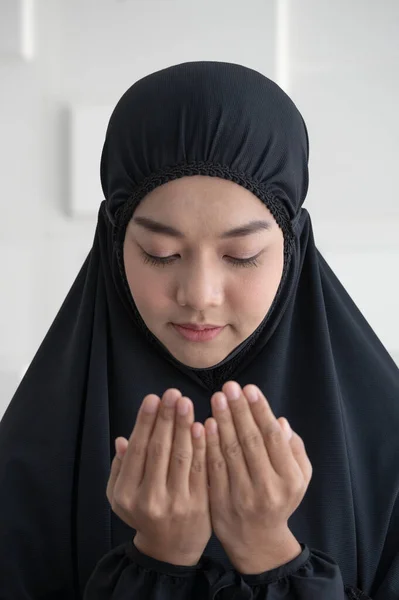 Asian young Muslim woman praying.